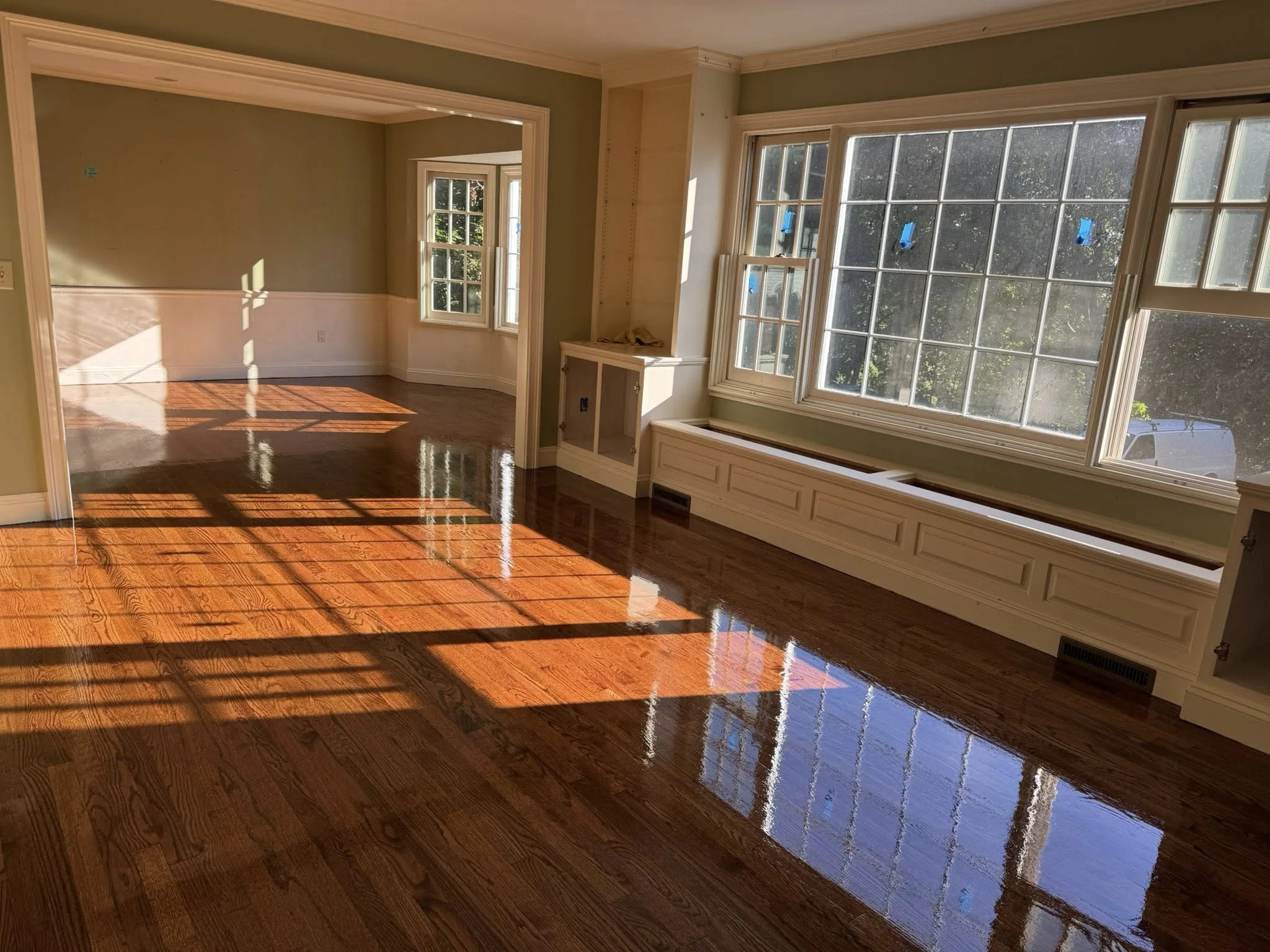Professional hardwood floor refinishing around built-in cabinetry and fireplace