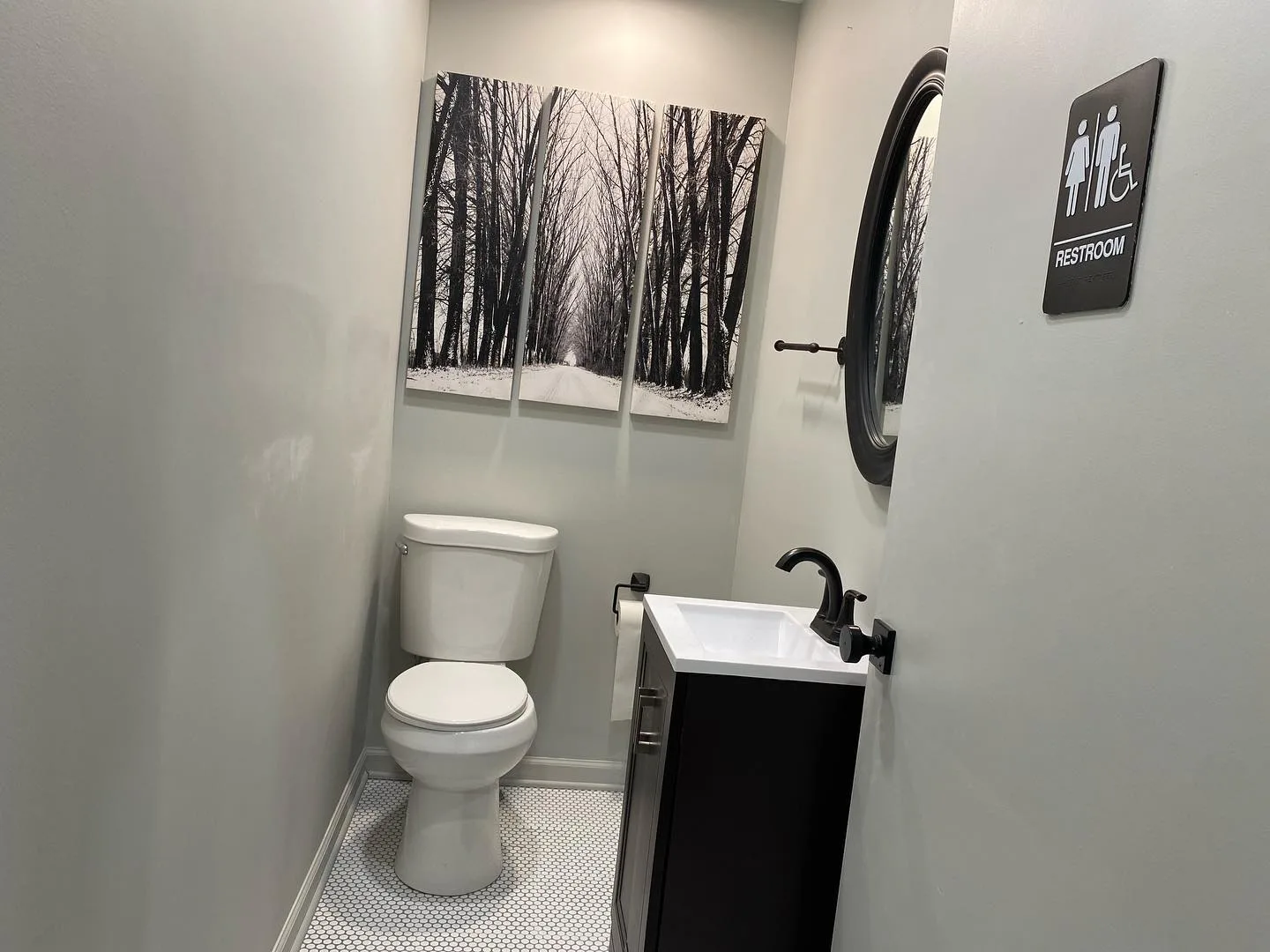 View of a toilet, black vanity, and wall art in a completed commercial bathroom Stratford CT.