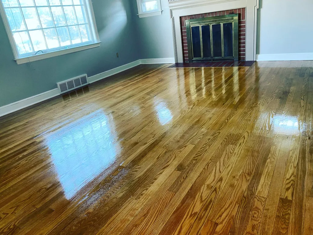 Refinished oak floors meeting a classic brick fireplace, a key feature of this hardwood floor refinishing job.