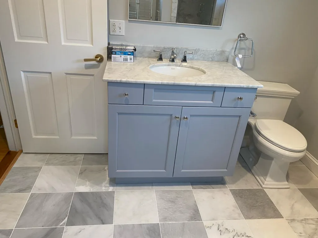 Grey bathroom vanity with a marble top over the marble tile floor installation.
